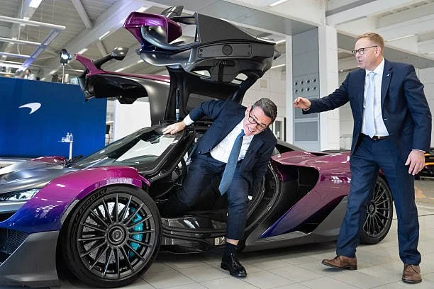 Премьер-министр Энди Бернхэм сидит в спортивном автомобиле McLaren W1 в сопровождении генерального