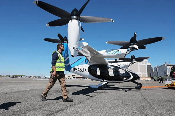 Рабочие и летчик-испытатель готовят электрический самолет Joby Aviation к взлету из аэропорта имени