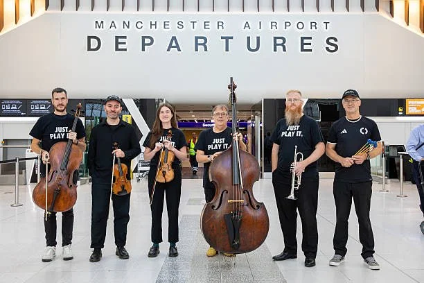 Участники оркестра Manchester Camerata позируют перед выступлением во время исполнения композиции